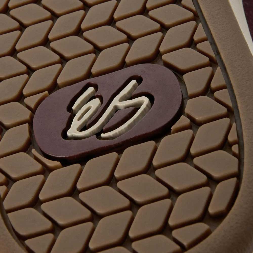 Close-up of the Accel Burgundy White Suede Es Skateboarding Shoe’s brown sole, featuring a textured hexagonal pattern and maroon oval with the white éS logo—signature details of this classic skate favorite.