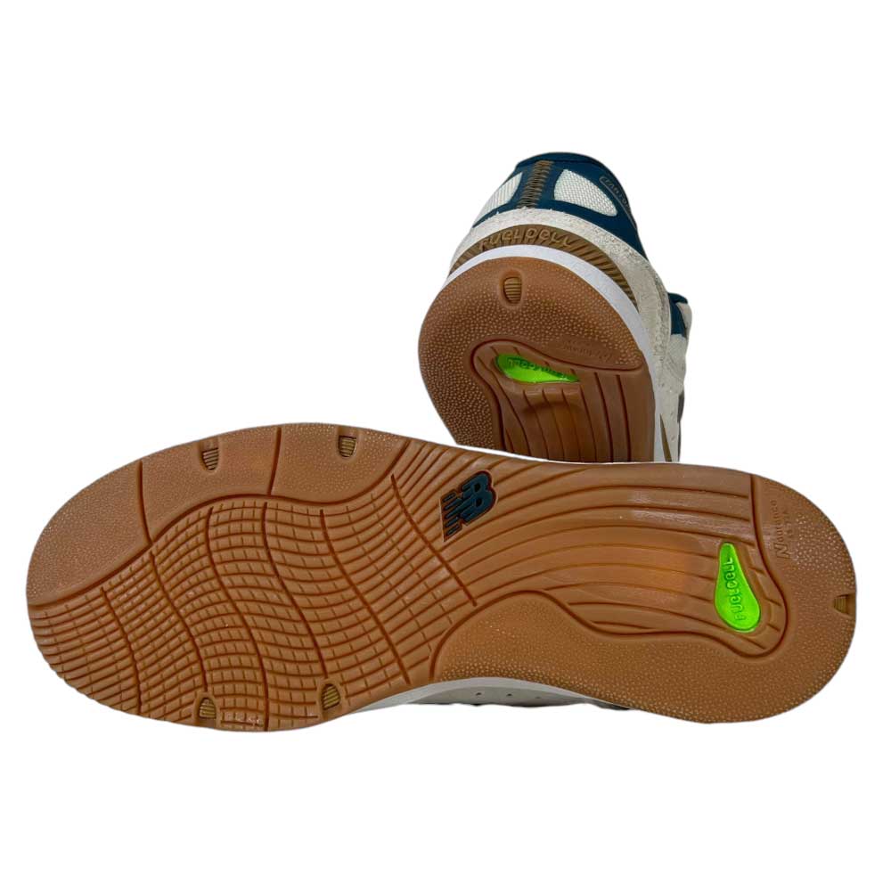 The image shows the soles of the 1010 BL Tiago Lemos Beige Blue Suede New Balance Numeric Skateboarding Shoes, with tan rubber outsoles, textured patterns, green inserts, and a black New Balance logo—perfect for skateboarding.