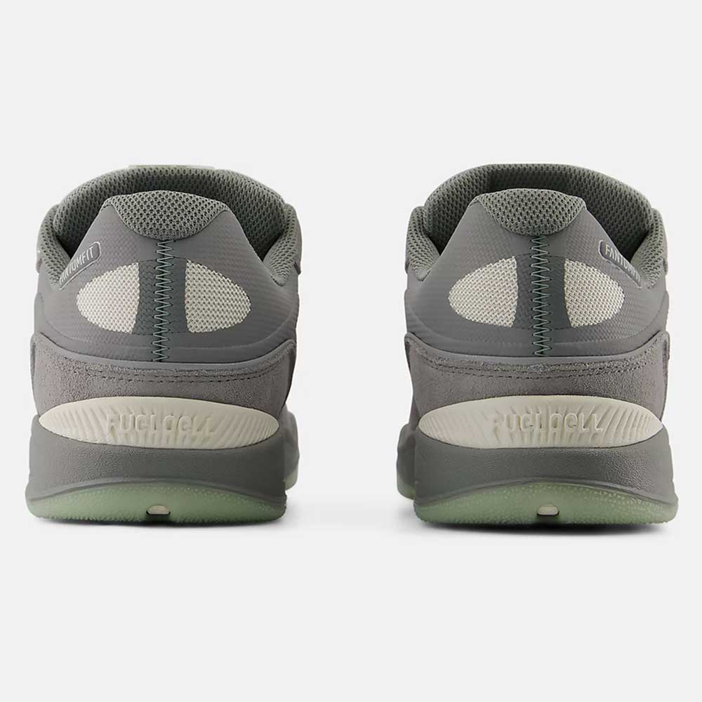 A pair of 1010 PS Tiago Lemos Slate Grey Sea Salt New Balance Numeric Suede Skateboarding Shoes are shown from the back, featuring mesh panels, textured soles with ABZORB midsoles, and a white floor underneath.