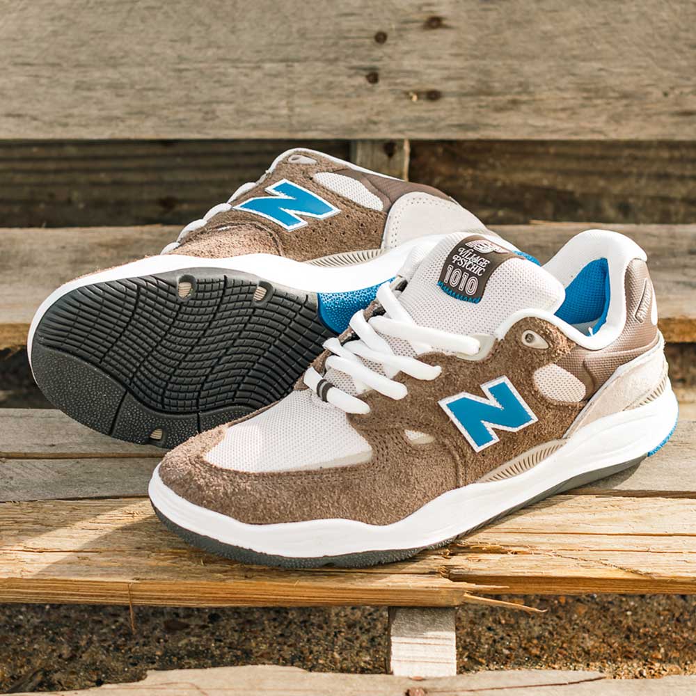 The 1010 SV Village Psychic Tiago Lemos Gray Blue Suede New Balance Numeric Skateboarding Shoes are displayed outdoors on a wooden bench, with one shoe upright and the other on its side.