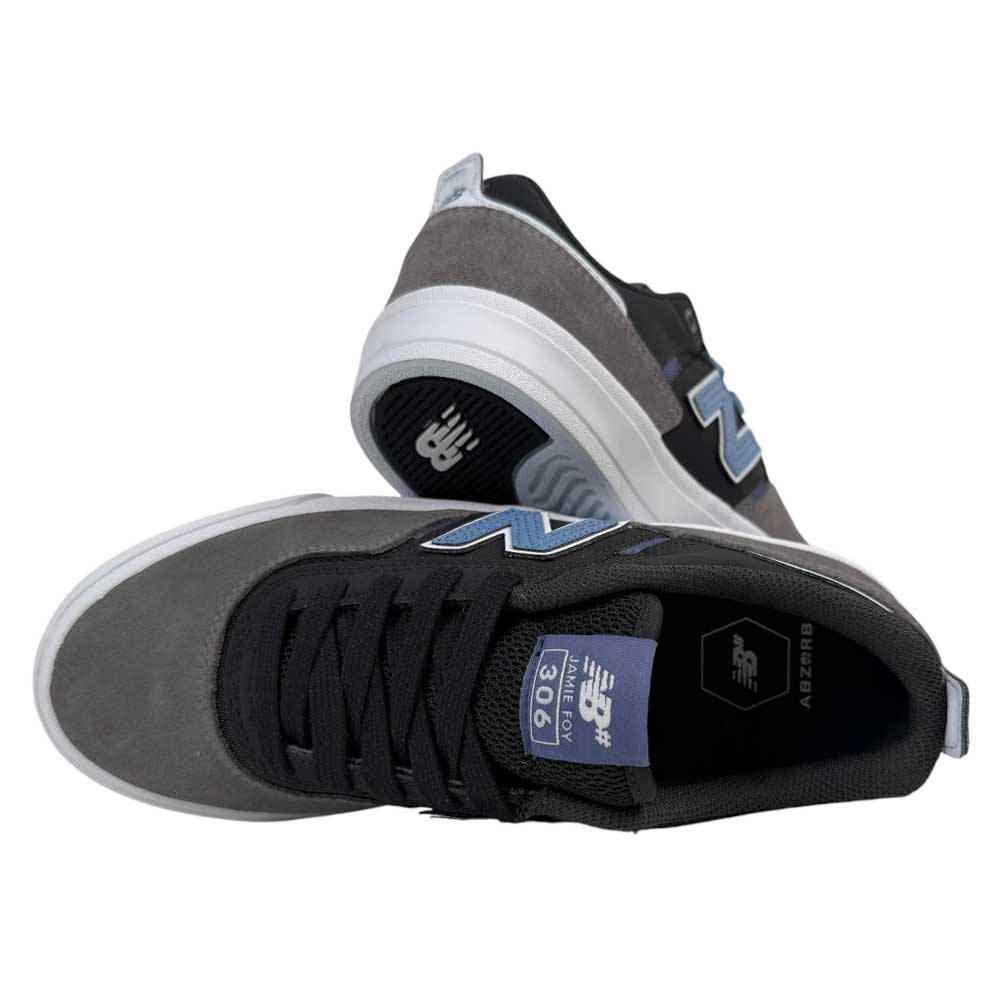 A pair of 306 TRI New Balance Numeric Jamie Foy Suede Shoes in Grey Black—premium skate sneakers with black laces and blue accents, shown upright and on their side to display the sole and side logo.