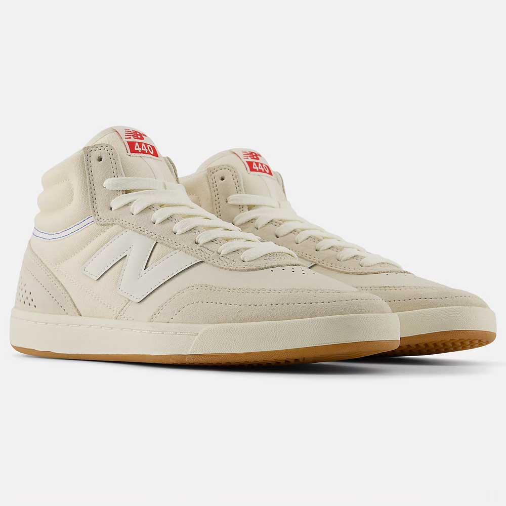 A pair of 440 HTW Timberwolf White New Balance Numeric suede skateboarding shoes featuring beige uppers, white laces, gum soles, red tongue labels with branding, and an ABZORB midsole for superior cushioning.