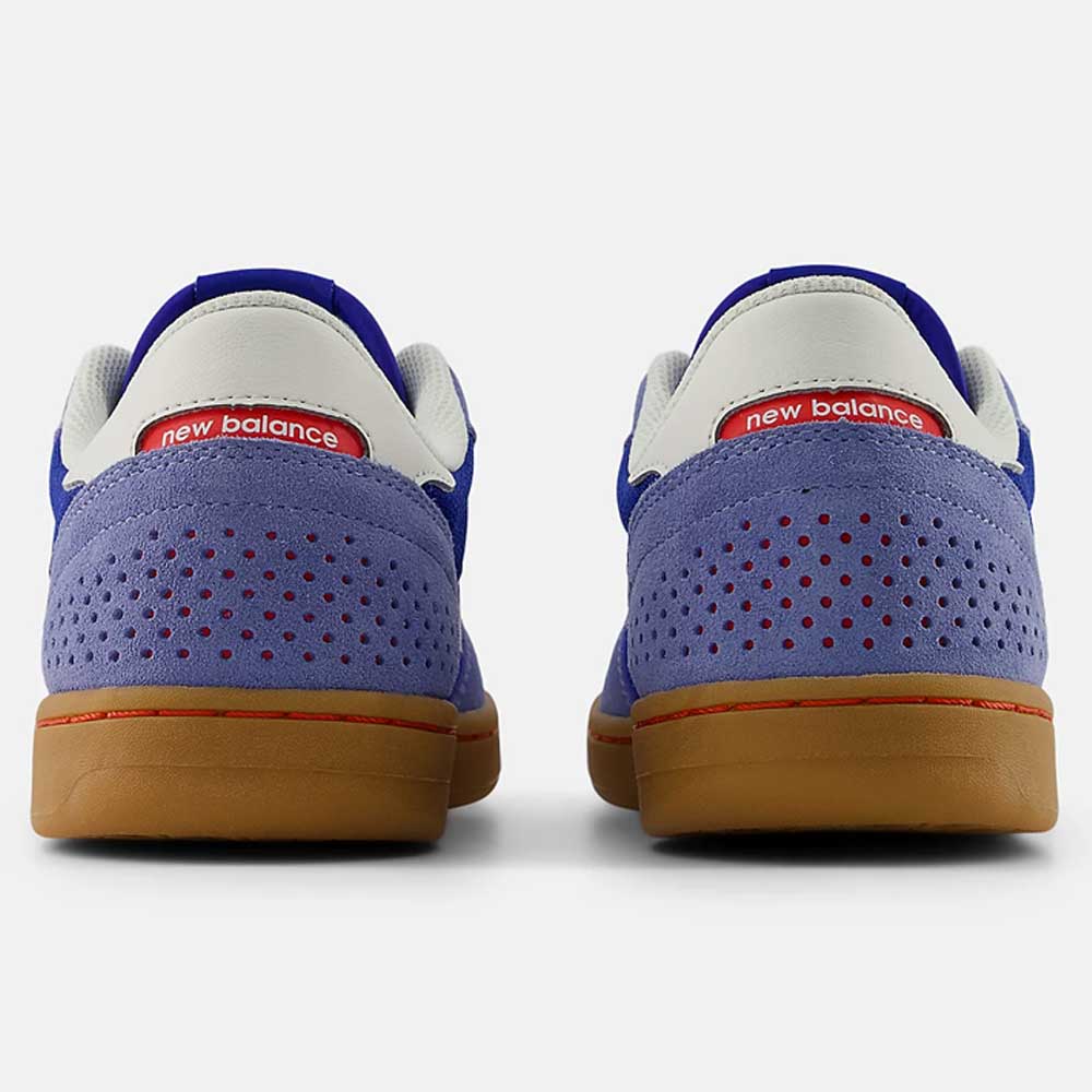 A pair of 440 RTB Blue Gum New Balance Numeric Suede Skateboarding Shoes viewed from the back, with purple suede heels, perforated holes, gum soles, white collars, red logo tags, and a comfy ABZORB midsole.