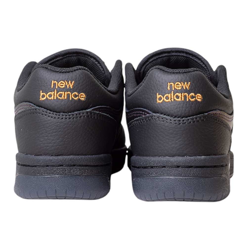 A pair of 480 BFK Bronze 56K New Balance Numeric Skateboarding Shoes in Suede Black Iridescent, shown from the back with gold New Balance text embroidered on the heels and a durable leather upper.