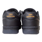 A pair of 480 BFK Bronze 56K New Balance Numeric Skateboarding Shoes in Suede Black Iridescent, shown from the back with gold New Balance text embroidered on the heels and a durable leather upper.