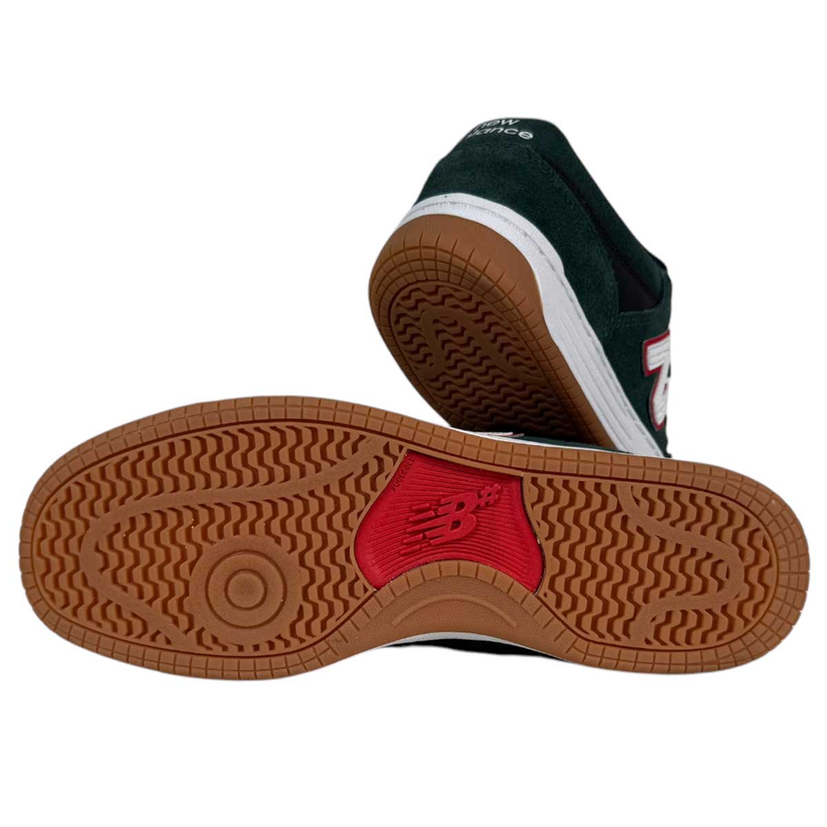 A pair of 480 FOY New Balance Numeric Shoes in suede green and black—one upright, one on its side—shows the gum-textured sole with a red NB logo and a white and red N logo on the durable leather upper for style and lasting performance.