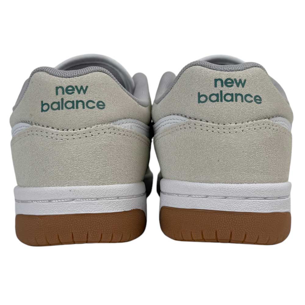 A rear view of 480 JDI New Balance Numeric Shoes in suede white and green, featuring durable leather, white midsoles, brown rubber outsoles, and green "new balance" text on the heels.