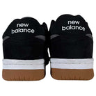 A pair of 480 MGC New Balance Numeric Shoes in Suede Black Dark Grey shown from the back, featuring a durable upper, white New Balance branding on the heels, white midsoles, and brown gum outsoles.