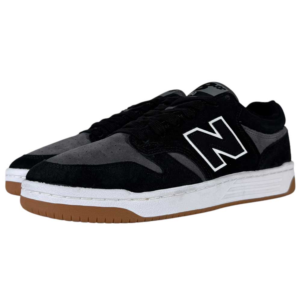 A pair of 480 MGC New Balance Numeric shoes in suede black and dark grey, featuring a durable upper, white midsoles, brown rubber outsoles, and a large white N logo on the side.