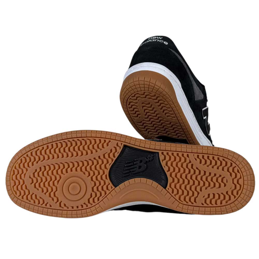 A pair of 480 MGC New Balance Numeric Shoes in Suede Black Dark Grey; one stands upright while the other is tilted to reveal the gum rubber tread and NB logo, showcasing a durable suede and leather upper for lasting wear.