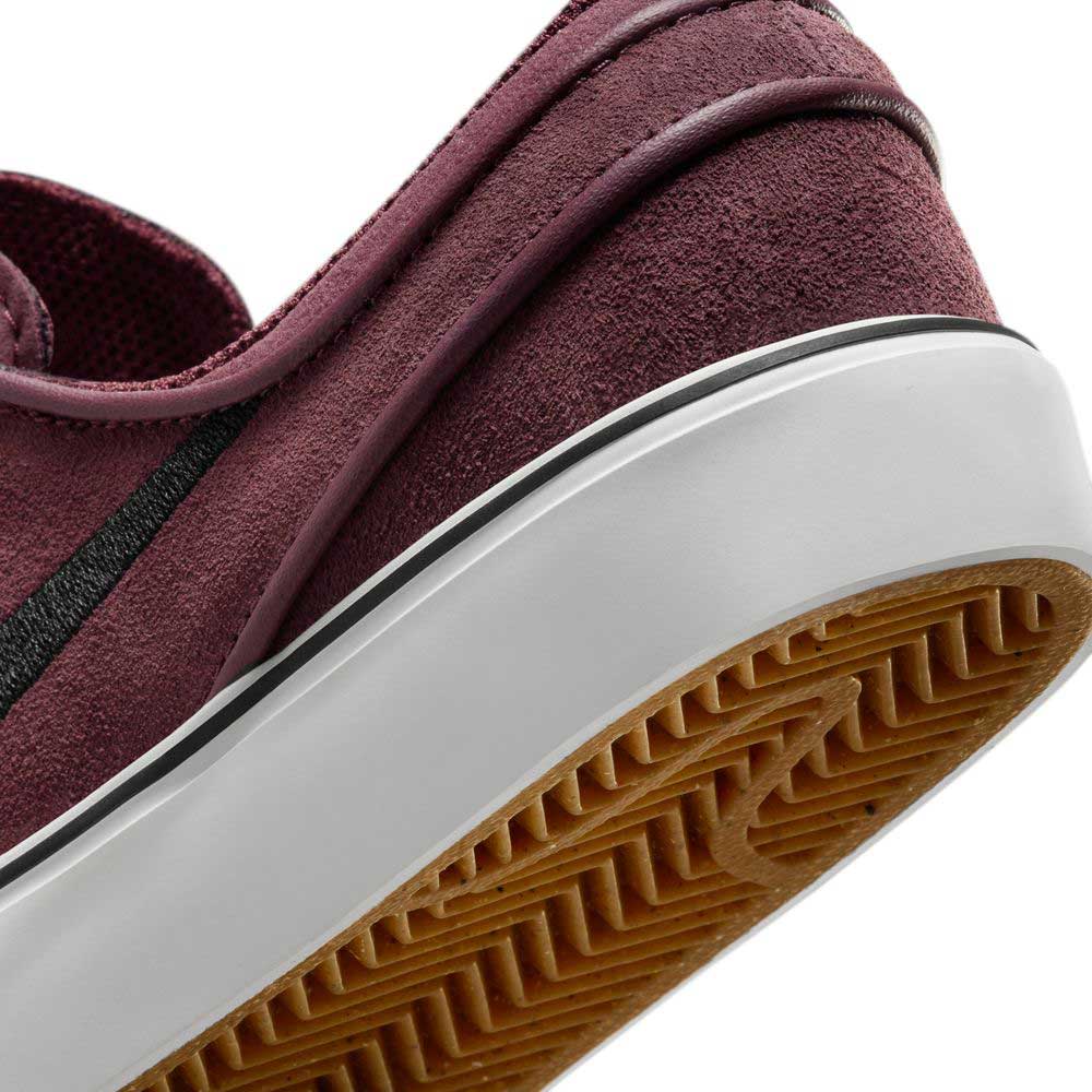 Close-up of the heel and sole on the Janoski GS YOUTH Burgundy Crush Black Suede Nike SB Skateboarding Shoes, featuring a white midsole, gum rubber outsole with black stripe, and detailed tread pattern, shown at a slight tilt.