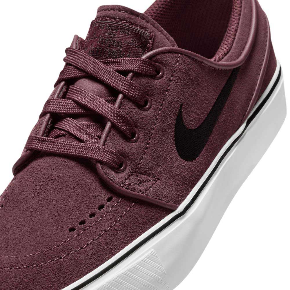 A close-up of the Nike SB Janoski OG 525104607 Burgundy Crush Black suede skateboarding shoe, featuring black laces, a black Swoosh, a white rubber sole with black stripe detail, and responsive Zoom Air cushioning.