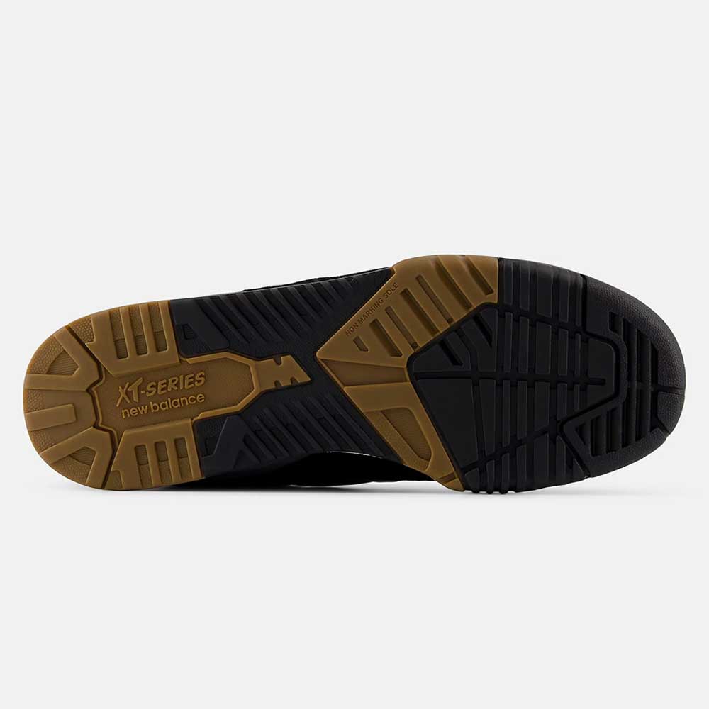The image shows the sole of a 770YZZ Black White New Balance Numeric Suede Skateboarding Shoe, featuring a tan and black rubber outsole with textured, grooved patterns for grip and stability, plus visible branding near the heel.