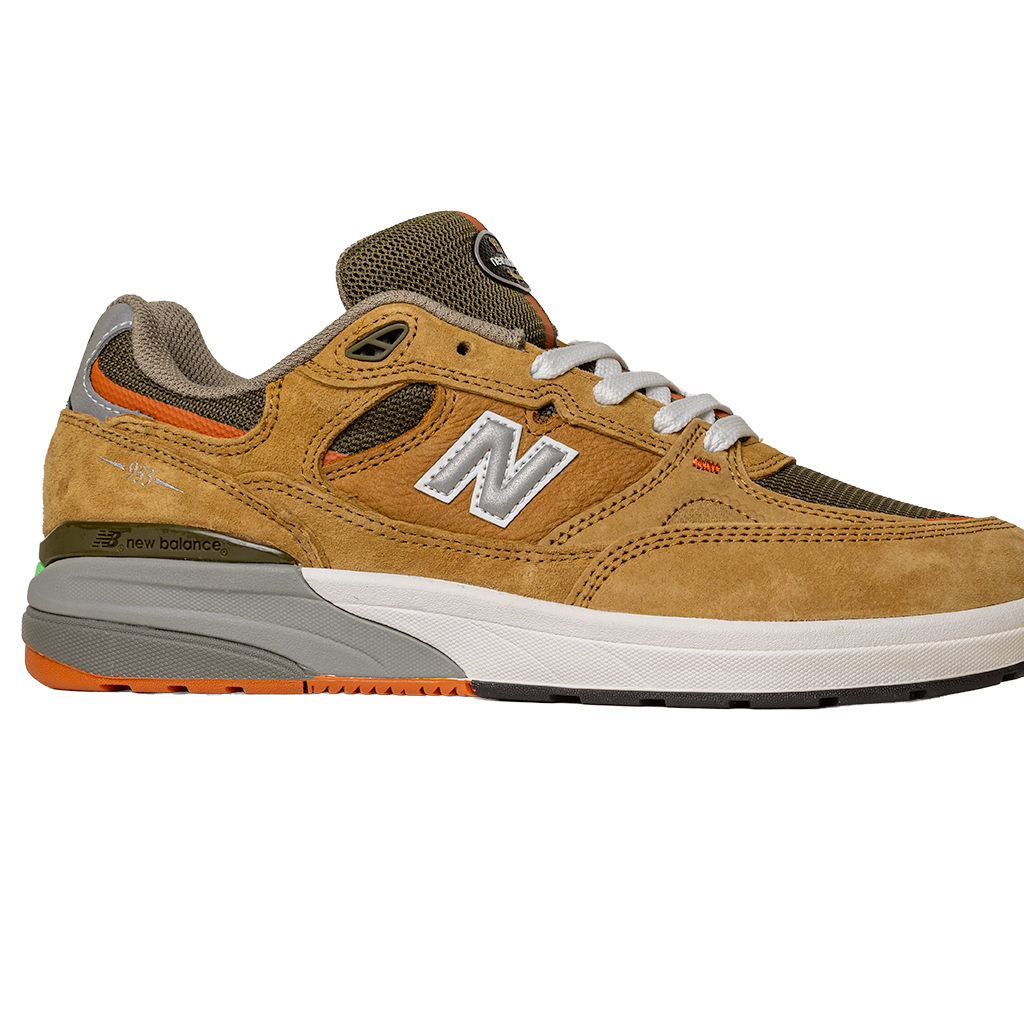 The 933 MNO Andrew Reynolds Brown Grey New Balance Numeric skateboarding shoe features suede and mesh panels, white laces, orange accents, and a gray-white sole, shown from the side on a plain white background.