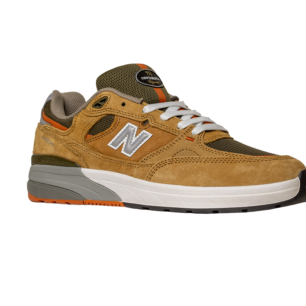 The 933 MNO Andrew Reynolds Brown Grey New Balance Numeric Skateboarding Shoes feature suede and mesh, white laces, a white and gray sole, orange accents, and a silver N logo—shown on a plain white background.