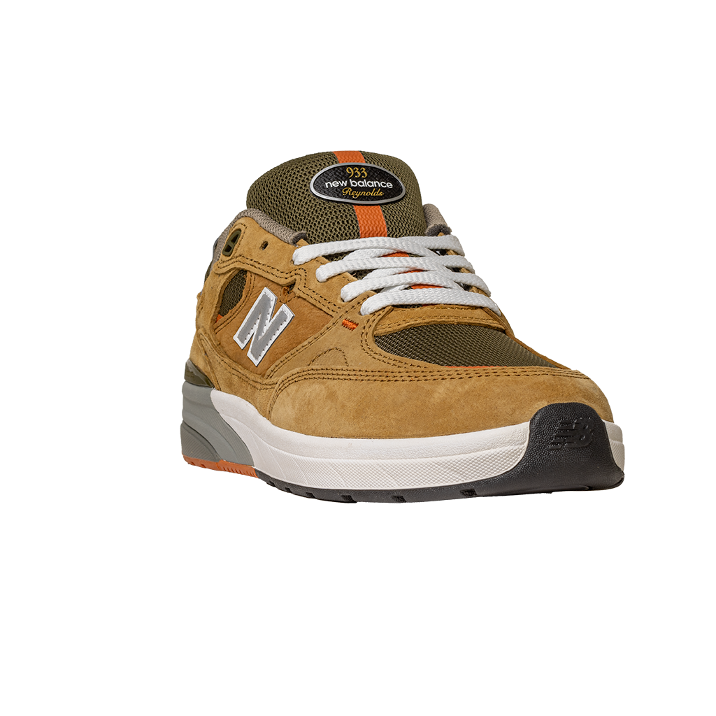 The 933 MNO Andrew Reynolds Brown Grey New Balance Numeric Skateboarding Shoes feature suede material, white laces, orange accents, and a white/black sole—shown from the front on a plain white background.