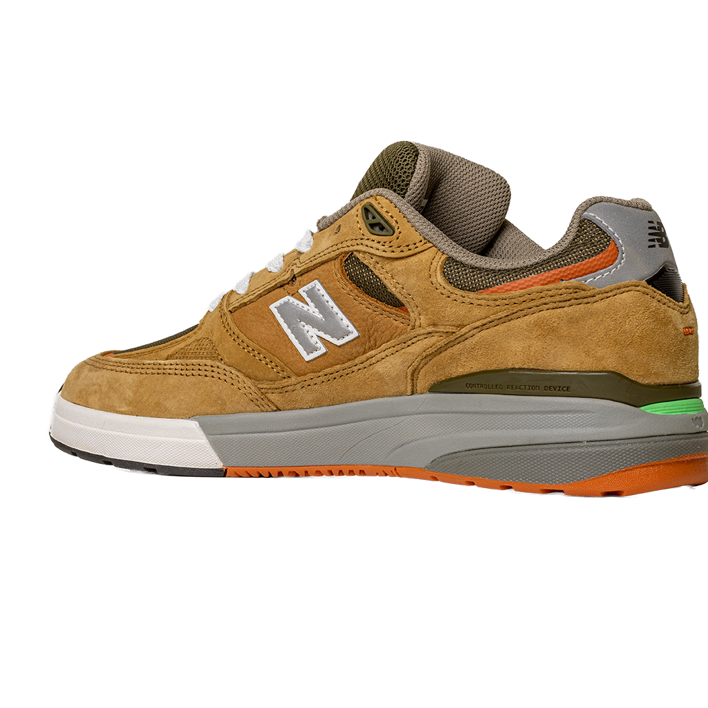The 933 MNO Andrew Reynolds Brown Grey New Balance Numeric skateboarding shoes feature brown suede with gray, green, and orange accents, a reflective N logo, white midsole, and textured gray and orange outsole, shown on a white background.