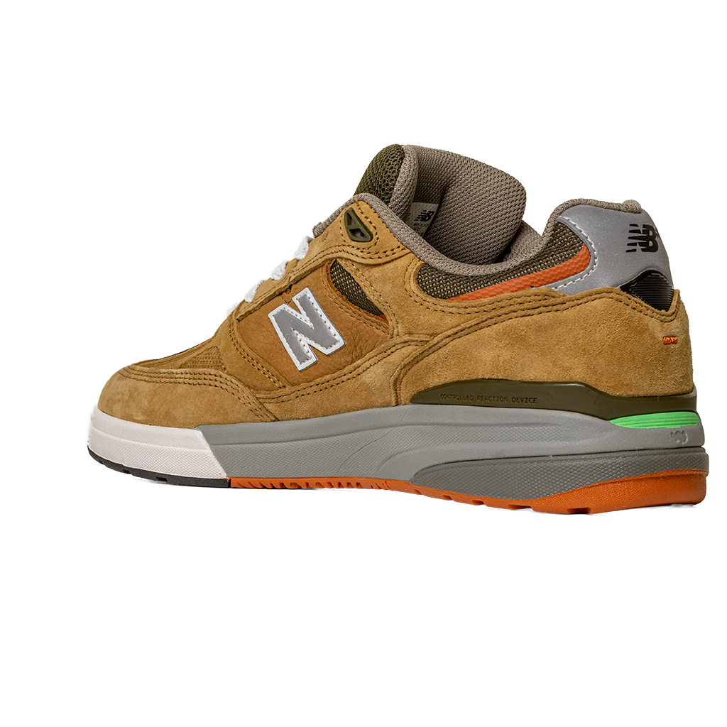 The 933 MNO Andrew Reynolds Brown Grey New Balance Numeric skateboarding shoe features tan suede, a white sole, gray and green midsole accents, an orange outsole, and a silver N logo, displayed on a plain white background.