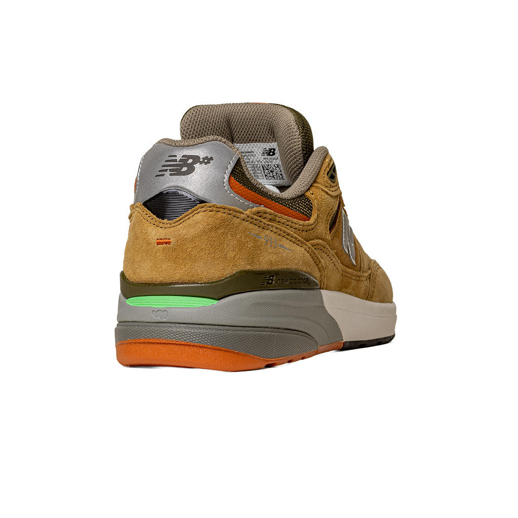 The 933 MNO Andrew Reynolds Brown Grey New Balance Numeric Suede Skateboarding Shoe is shown from the back, with a grey NB-logo heel, green and orange sole accents, beige midsole, and a tan suede upper against a white background.