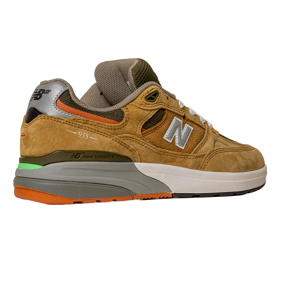 The 933 MNO Andrew Reynolds Brown Grey New Balance Numeric Skateboarding Shoes feature brown suede, gray accents, green and orange midsole details, white laces, and a white/gray sole, shown on a plain white background—ideal for skateboarding.