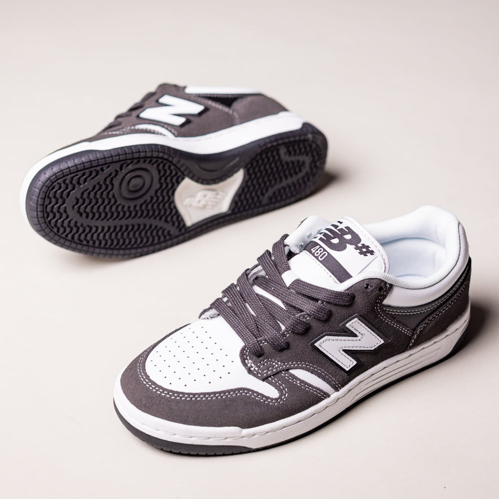 A pair of Black Cement White 480 BAB New Balance Numeric Suede Skateboarding Shoes—one upright showing the side and top, the other on its side highlighting the sole.
