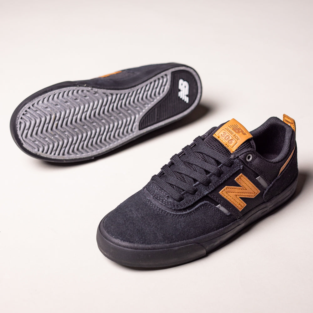 A pair of White Black 306 BON New Balance Numeric suede skateboarding shoes. One vulcanized shoe stands upright, displaying side and top views; the other lies on its side, highlighting the textured grip sole.
