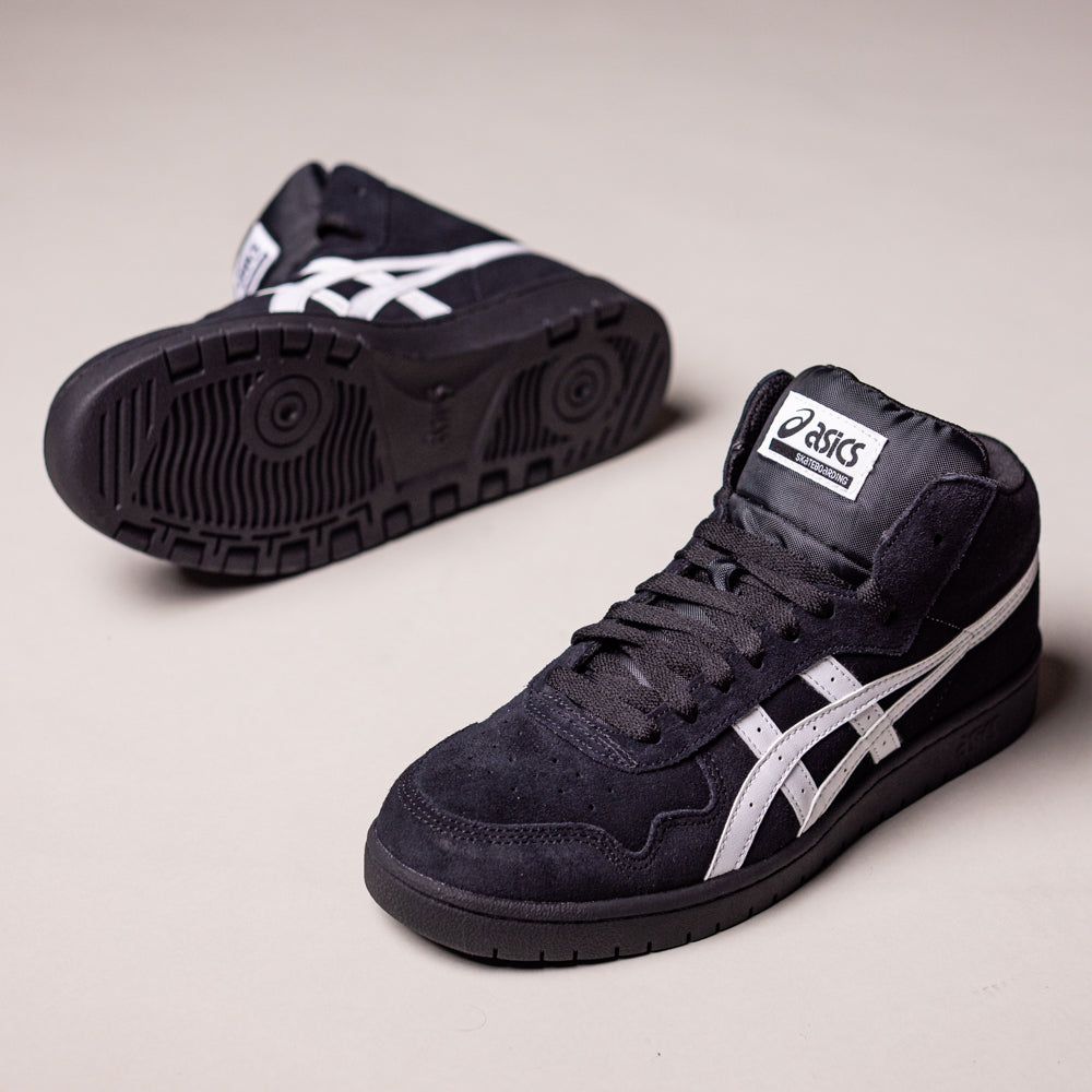 A pair of Japan Pro MT Asics Black Bright White 1201B003003 suede skateboarding shoes—black high-tops with white side stripes—one upright, one on its side showing the sole, on a plain light background.