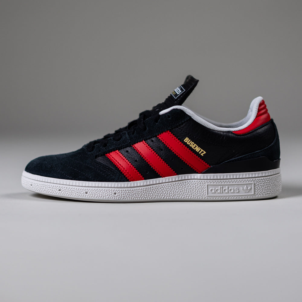 The JH8606 Black Betsc Busenitz Adidas Skateboarding Suede Shoes feature red stripes, a red heel detail, a white sole, and Busenitz in gold lettering, inspired by classic Copa Mundial skate shoes and shown on a neutral gray background.