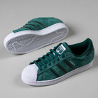 A pair of JQ1103 Core Green White Superstar ADV Adidas Skateboarding suede shoes, featuring white shell toes, white soles, dark green stripes, and laces, displayed on a light gray background.