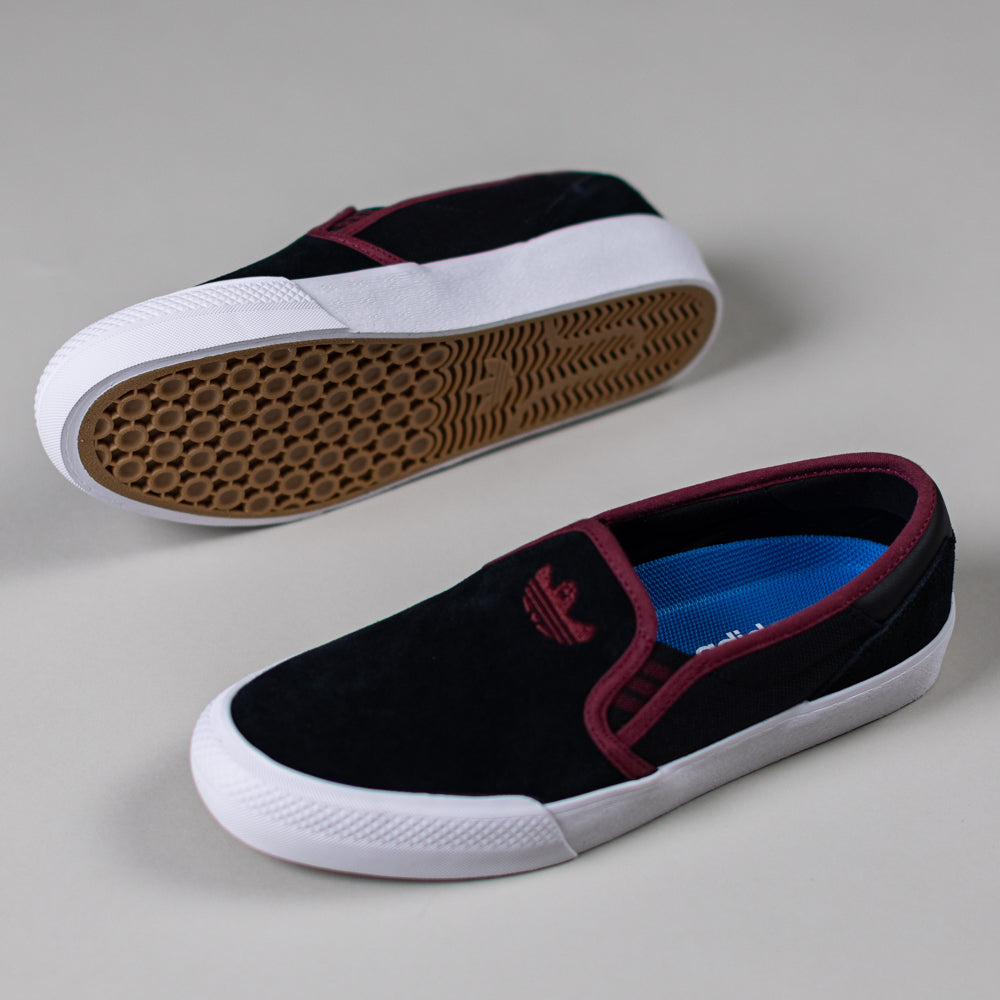 A pair of JQ1044 Black Share Shmoofoil Slip Adidas Skateboarding suede shoes with maroon trim, white rubber sole, and gum outsole—one upright showing the top, the other flipped to reveal the tread pattern.