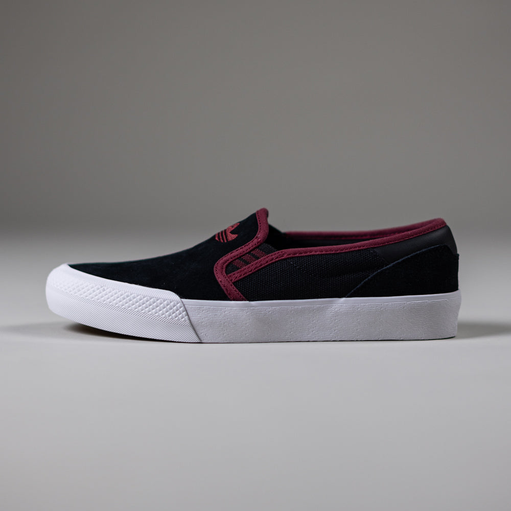 The JQ1044 Black Share Shmoofoil Slip Adidas Skateboarding Suede Shoe features a black suede slip-on design, white rubber sole, and burgundy trim, shown on a plain gray background.