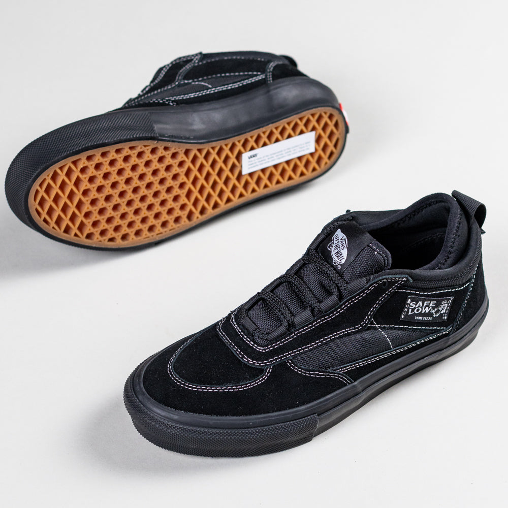 A pair of VN000EEHBKA1 Skate Safe Low Black Vans shoes—black suede with white stitching and gum waffle soles for grip; one lies on its side showing the sole, the other upright displaying the Safe Low label.