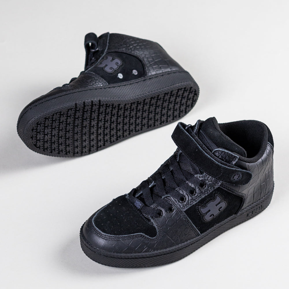 A pair of Grasshopper Black Croc Leather I Path Skateboarding Shoes, featuring textured patterned sides, lace-up fronts, Velcro straps, and a side logo; one shoe stands upright, the other lies sideways displaying the grippy sole.