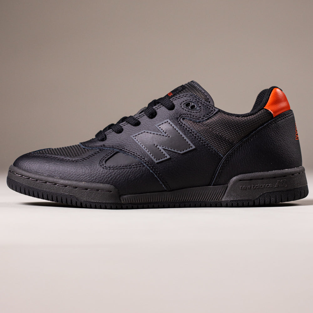 The 600TOO Black Orange Tom Knox New Balance Numeric Leather Skateboarding Shoes feature a textured design, mesh panels, and an orange heel accent, with responsive FuelCell foam for comfort and performance. Shown on a plain background.