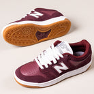 A pair of 480PRO Monarch Burgundy New Balance Numeric Suede Skateboarding Shoes, inspired by heritage basketball, with white laces, white midsoles, gum rubber outsoles; one shoe stands upright, the other displays its sole.