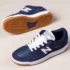A pair of 480BEE Navy White New Balance Numeric suede skateboarding shoes with gum rubber soles, white laces, and the signature N logo, blending classic heritage style on a light background.
