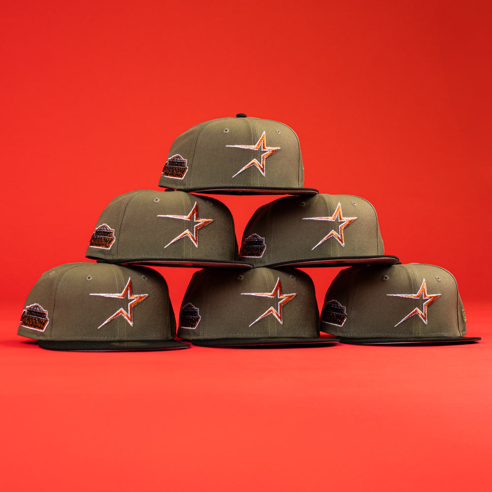 Five The Original Olive Black CC Astros New Era Hat 5950 Fitted caps, with orange star logos and black bills, form a pyramid against a red background. Each features a black patch on the left side.