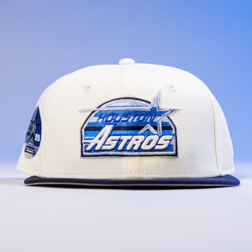 The KB1 Rushmore 35th Chrome Navy Houston Astros New Era 5950 Fitted Hat features a white crown, navy blue brim, and a blue and silver Astros logo on the front set against a gradient blue background.