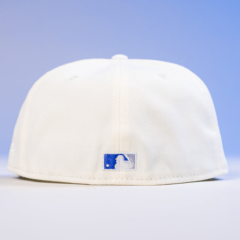 The KB1 Rushmore 35th Chrome Navy Houston Astros New Era Hat 5950 Fitted is shown back facing forward, with a small blue and white rectangular logo above the brim, set against a blue and white gradient background.