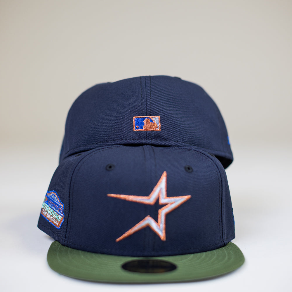 The Aquamarine Navy Rifle Green Astros New Era Hat 5950 Fitted showcases a bold star front logo, green brim, and vibrant side patch, with another cap featuring a small rectangular stacked logo behind it.