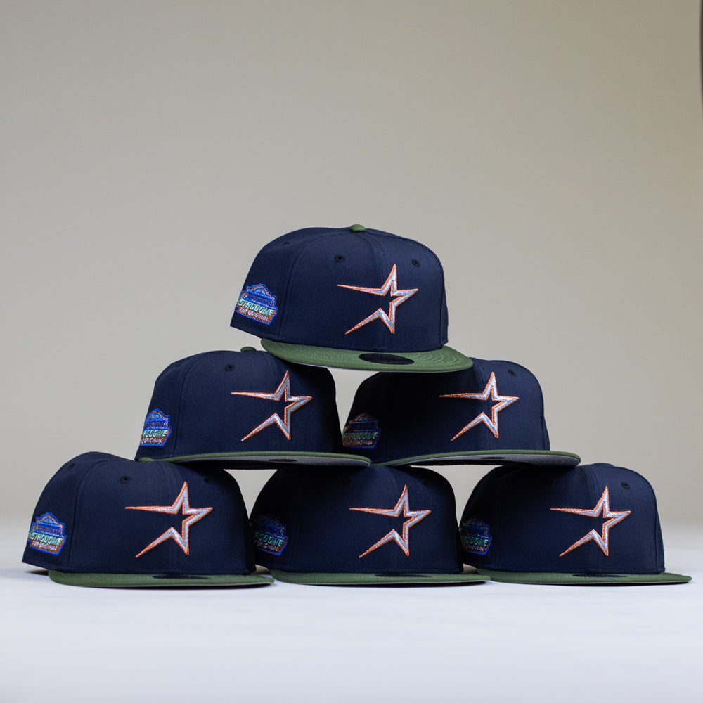 Six Aquamarine Navy Rifle Green Astros New Era Hat 5950 Fitted caps featuring an orange and white star logo are stacked in a pyramid shape against a plain background.