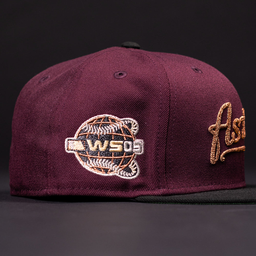 The 05 Debut Maroon Black Houston Astros New Era 5950 Fitted Hat features a gold logo, black brim, and an embroidered World Series '09 baseball patch on the side, displayed against a dark background.