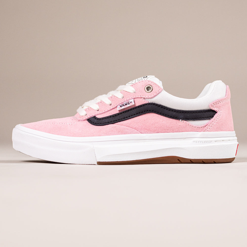The VN000DA4PNK1 Skate Kyle Walker Wafflecup Pink Vans features pink suede, white laces, a black side stripe, and a white rubber sole. Inspired by skateboarding, this profile-view sneaker is set against a plain beige background.