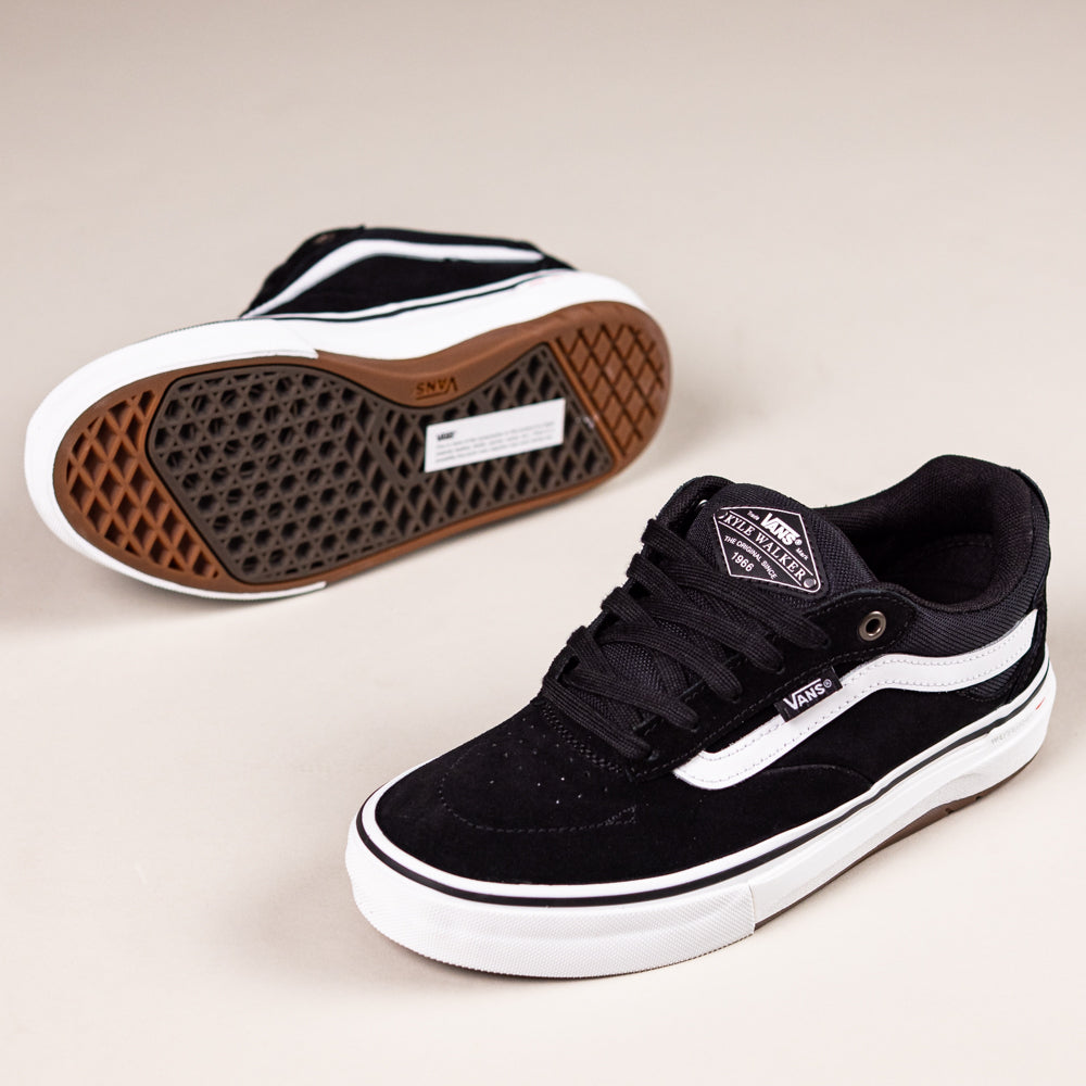 A pair of VN000DA4MCG1 Skate Kyle Walker Wafflecup Black White Vans shoes in suede with white soles and signature side stripe. One shoe is upright, showing top and side; the other lies sideways, displaying the brown waffle-patterned sole.