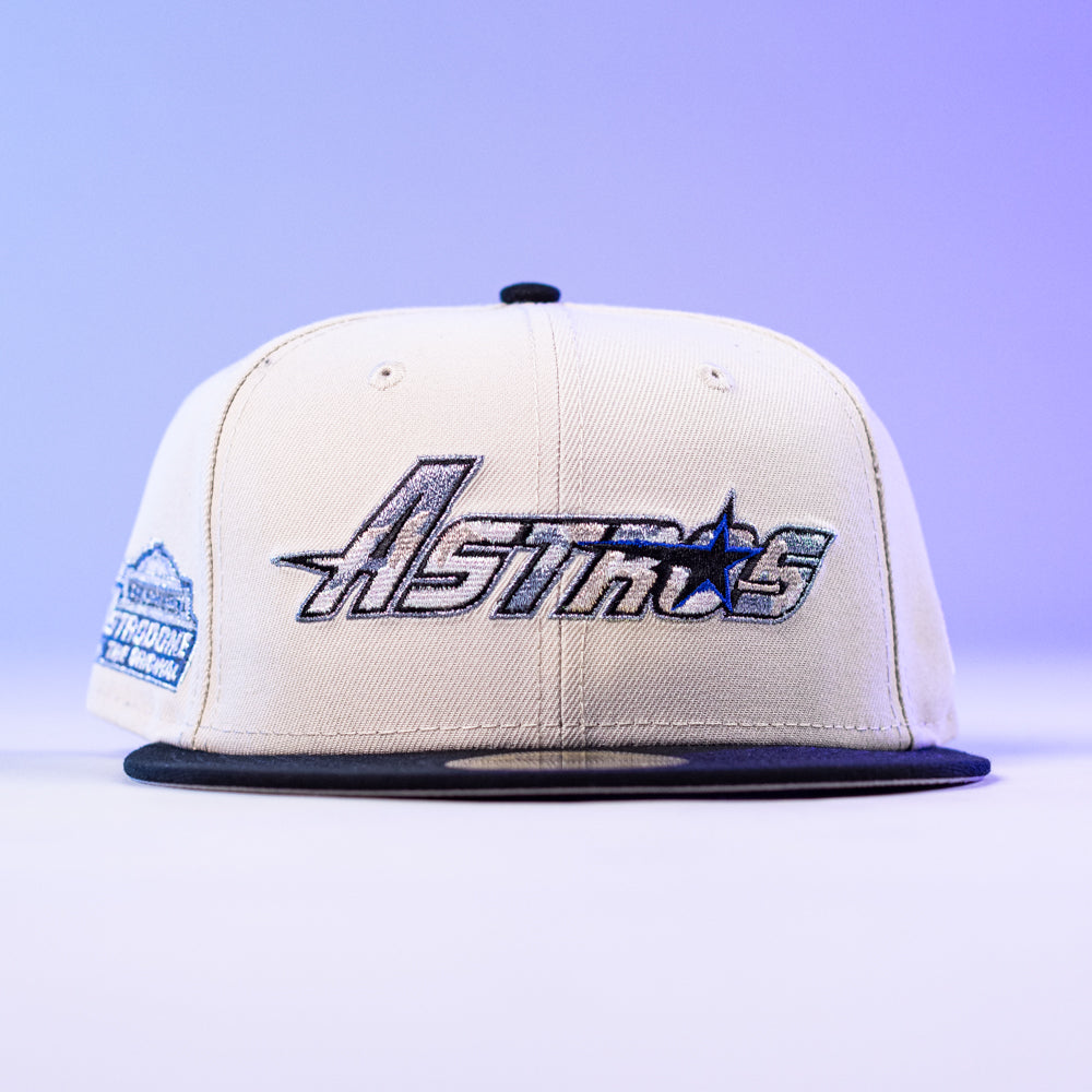 The SNOFALL Blue Camo Houston Astros New Era 5950 Fitted Hat features a camo pattern with the Astros logo. This stylish cap is displayed on a light surface with a purple gradient background.