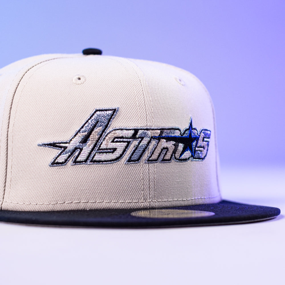 A close-up of the SNOFALL Blue Camo Houston Astros New Era 5950 Fitted Hat, featuring bold Astros embroidery on the front with a stylish blue camo design, displayed against a soft purple background.
