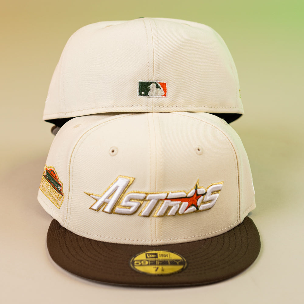 Two Oompa Pink Box Houston Astros New Era 5950 Fitted hats are shown. Both have cream panels and brown brims; the front cap features the Astros logo and a commemorative patch, while the back shows the MLB logo above the closure.