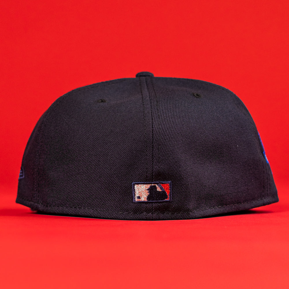 A 6am in Texas Navy Red White New Era Hat 5950 Fitted is displayed against a red background, showing the back of the cap with the MLB logo embroidered at the center bottom.