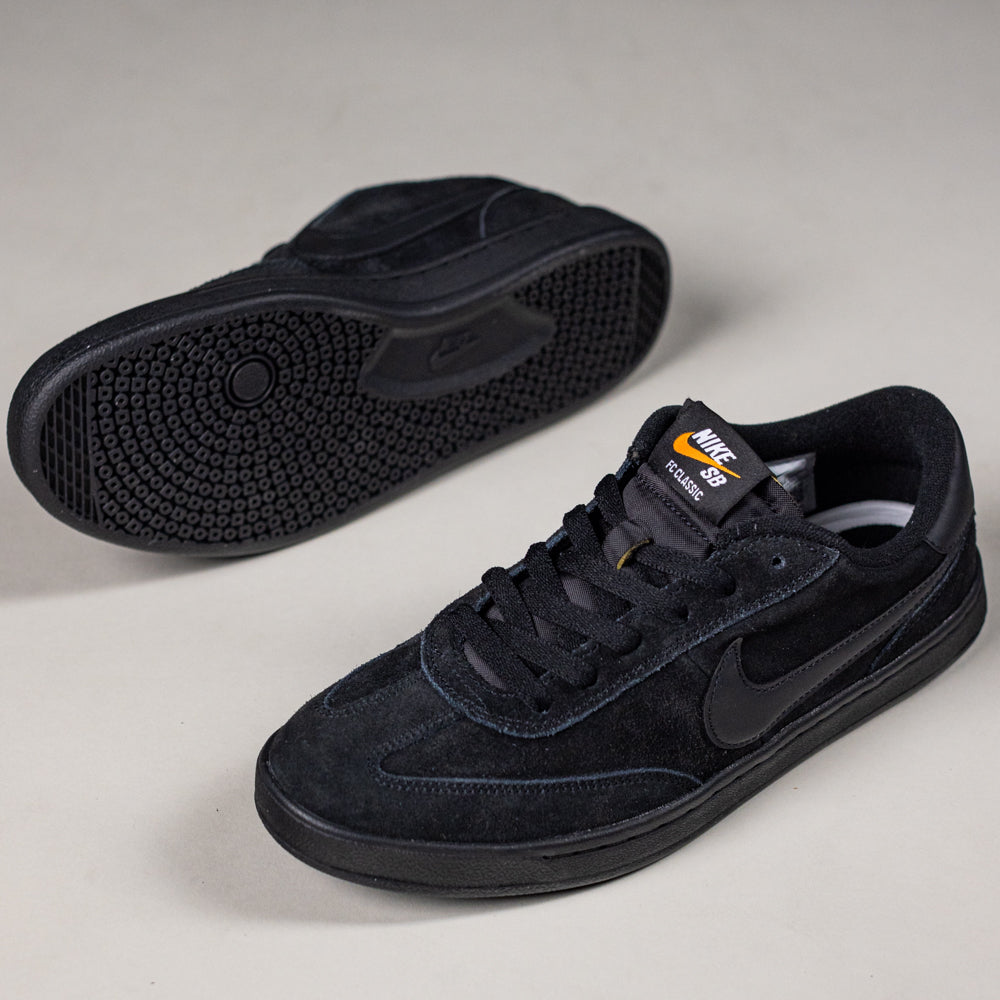 A pair of 909096002 Black Vivid Orange FC Classic Nike SB suede skate shoes: one upright showing the side, the other on its side displaying the textured rubber sole and hinting at the comfort of a Solarsoft insole.