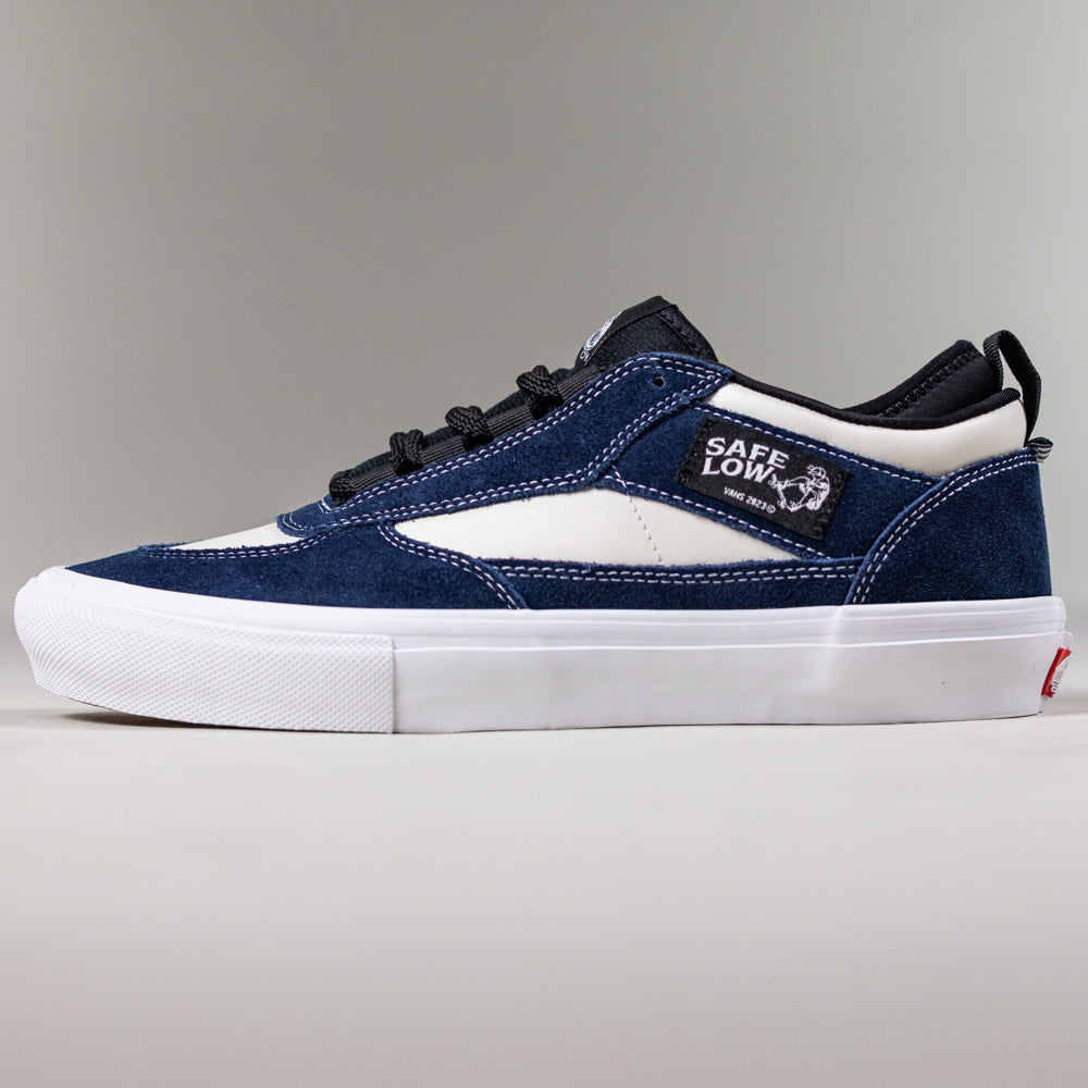 The VN000EEHFRP Skate Safe Low Navy Marshmallow Vans shoe features navy and white suede uppers, black laces, a white rubber sole, "SAFE LOW" on the side panel, durable low-top design, and a red logo on the heel.